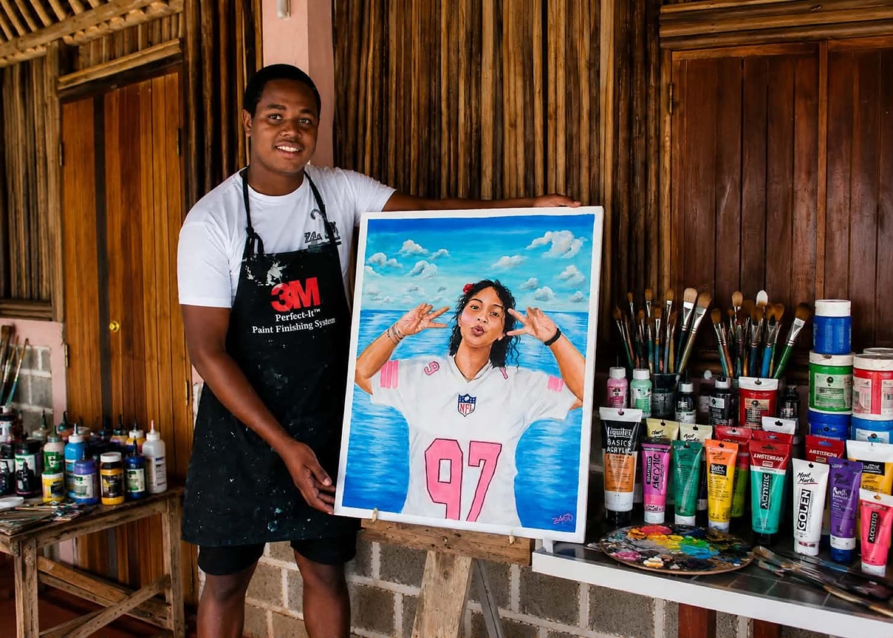 Zago présente un portrait réalisé sur commande d'après une photographie, une jeune femme en maillot de sport devant la mer, entouré de ses tubes de peinture et de ses pinceaux.